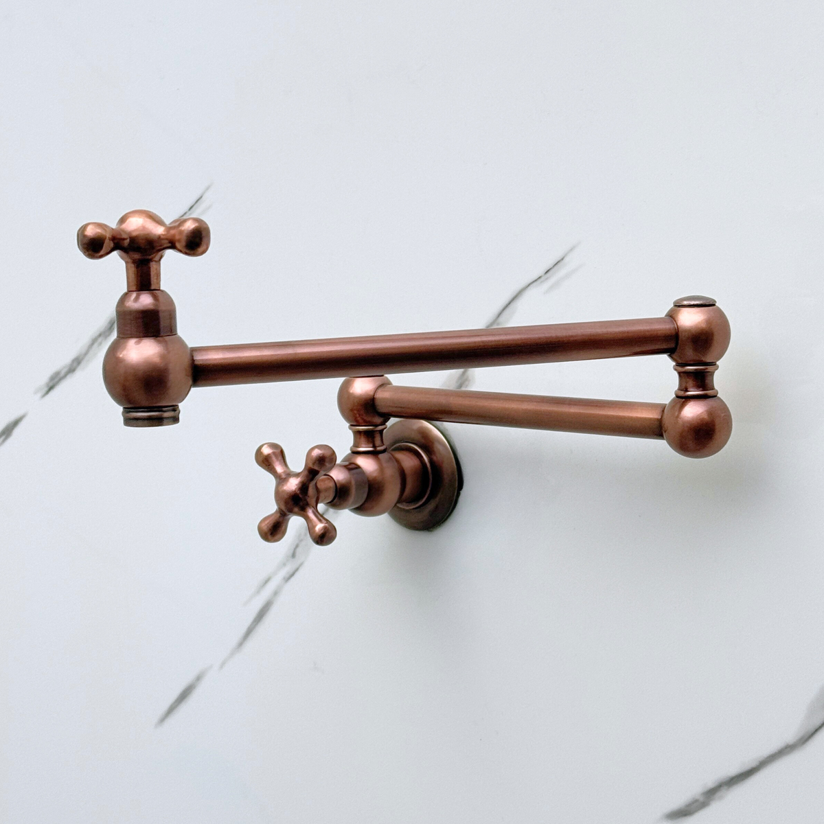 Antique copper cross-handle pot filler in a kitchen setting