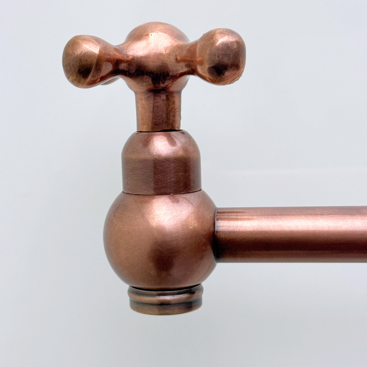 Antique copper pot filler extended over kitchen range