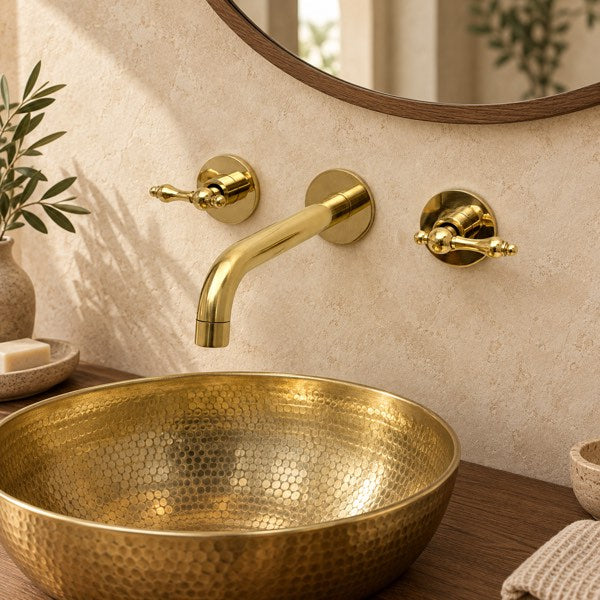 Brass wall faucet and basin in a coordinated warm stone bathroom